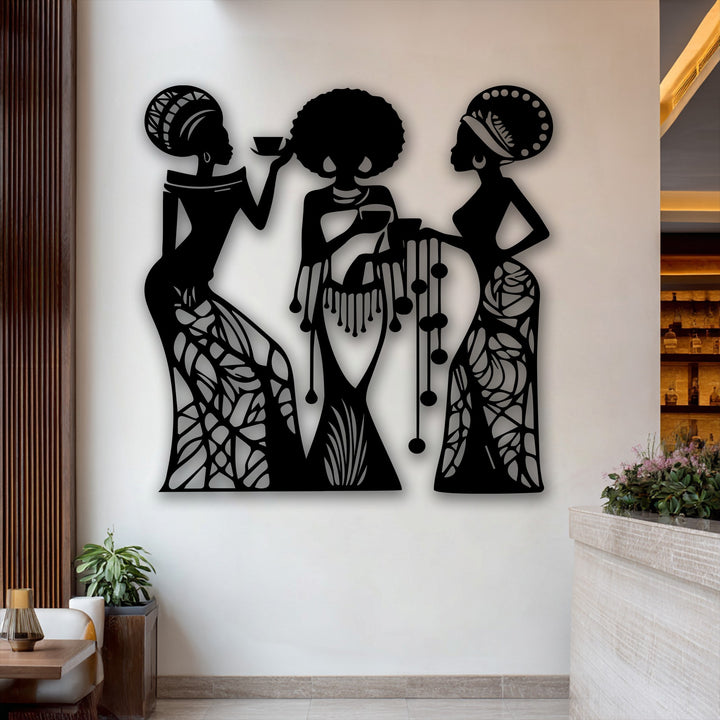 Color saturation is low in this image, highlighting the unique metal wall art of three detailed female silhouettes against a neutral wall.