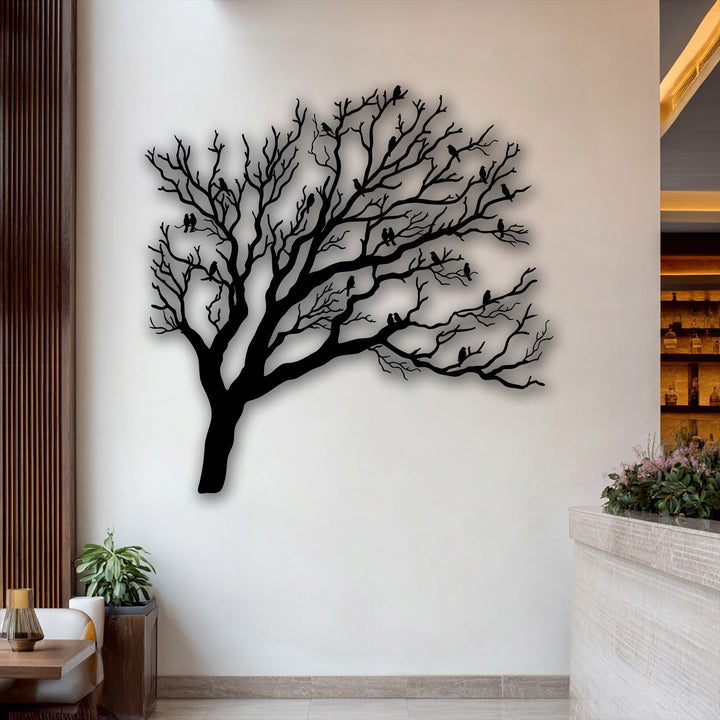 The pristine, light wall background, subtly accented by wood, showcases the unique metal wall art of a bare tree with birds silhouette.