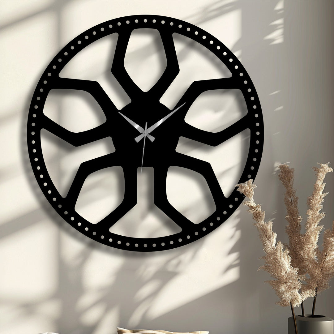 Dried, wispy light brown ornamental grass in a dark vase foregrounds the striking abstract radial pattern metal wall decor.