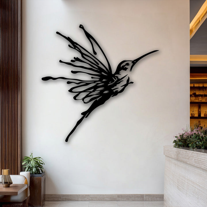 The surface texture of this flying hummingbird metal artwork is smooth and dark, contrasting sharply with the light wall, creating an elegant bird design.