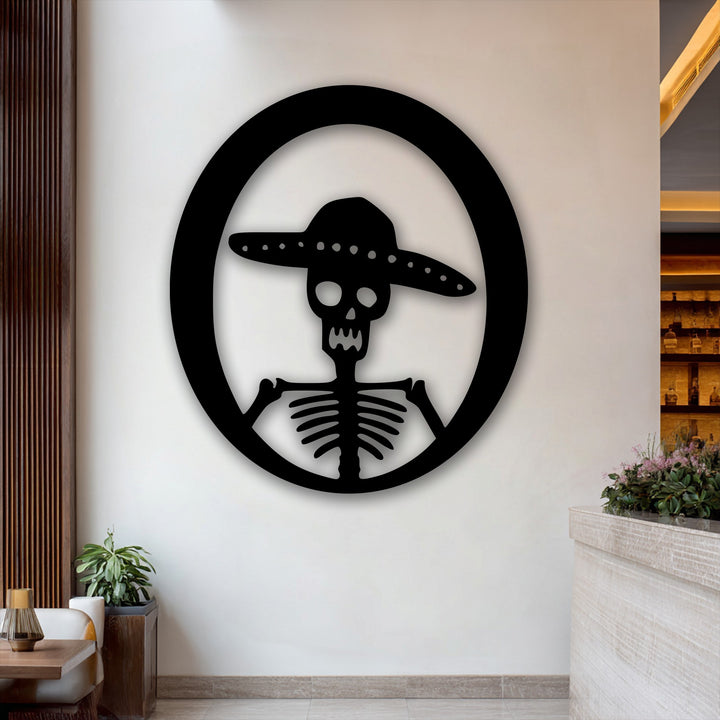 The muted color saturation highlights the stark black Sombrero Skeleton unique metal wall art against a neutral backdrop.