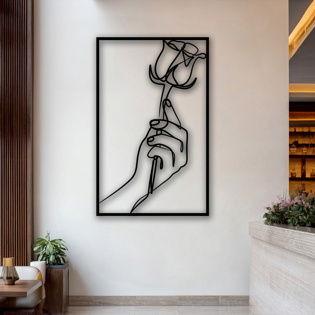 Delicate pink blossoms and lush green foliage beautifully contrast with the bold minimalist hand holding a rose in sleek decorative metal art.