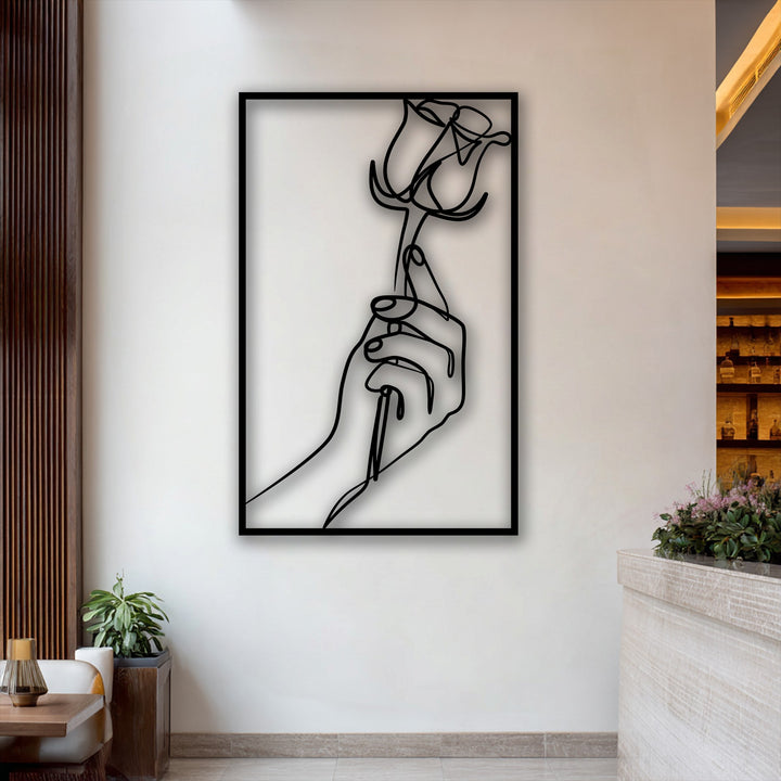 Delicate pink blossoms and lush green foliage beautifully contrast with the bold minimalist hand holding a rose in sleek decorative metal art.