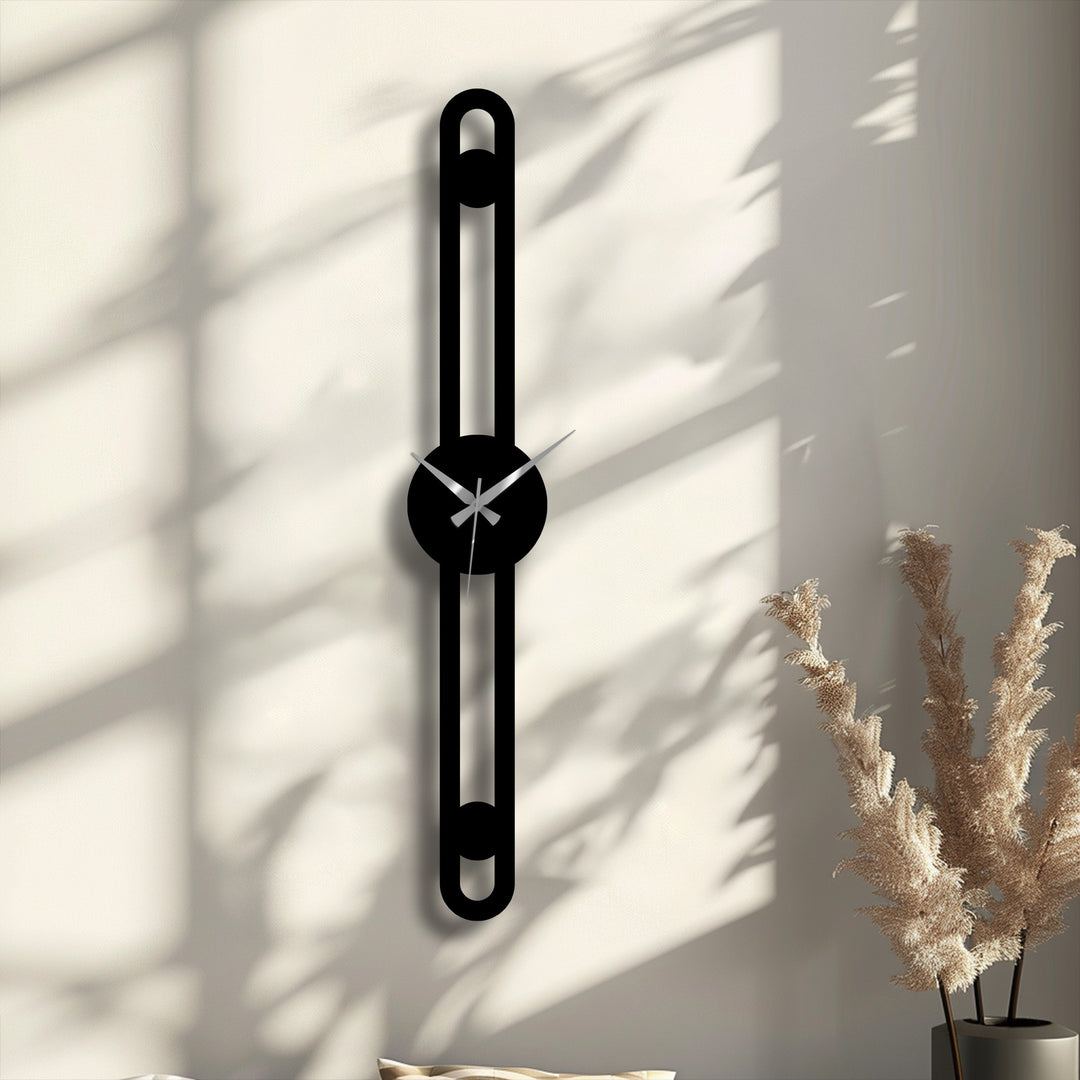 Dried beige pampas grass in a dark vase stands in the foreground, complementing the minimalist vertical metal artwork clock on the wall.