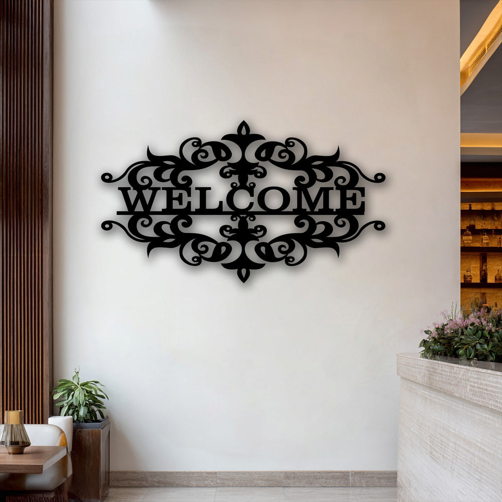 The ornate black welcome emblem, a piece of decorative metal art, features intricate flourishes and casts a shadow on the clean white wall.