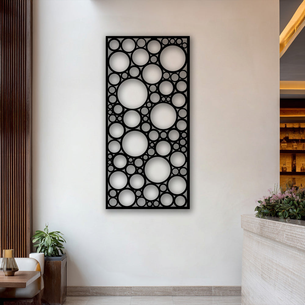 The softest element, a lush potted plant, adds natural contrast to the bold geometric circle pattern panel metal wall decor.