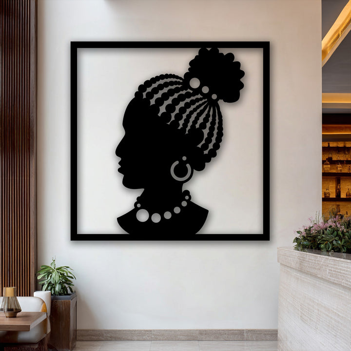 A bright white wall, subtly accented with warm wooden paneling, forms the backdrop for the elegant African woman unique metal wall art.