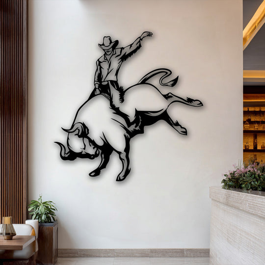 The warm color temperature enhances the dynamic black cowboy bull riding metal wall decor against a bright wall, complemented by inviting wooden accents.