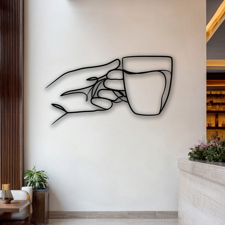 A prominent minimalist line art metal artwork depicting a hand delicately grasping a cup on a light wall.