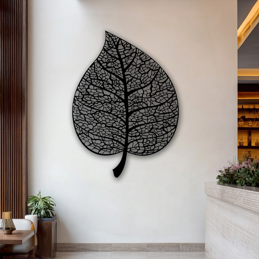 The striking black intricate botanical leaf silhouette, a decorative metal art piece, dominates the pristine white wall.