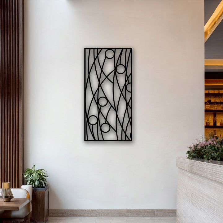 The focal point is a striking black abstract linear geometry metal artwork featuring circles, mounted on a pristine white wall.
