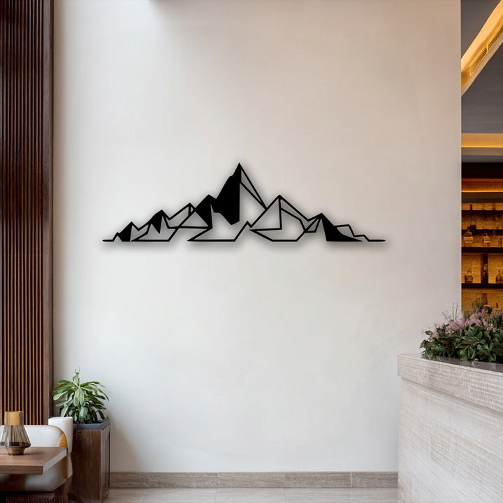 The negative space around the black geometric abstract mountain decorative metal art creates a striking minimal line design on a white wall.