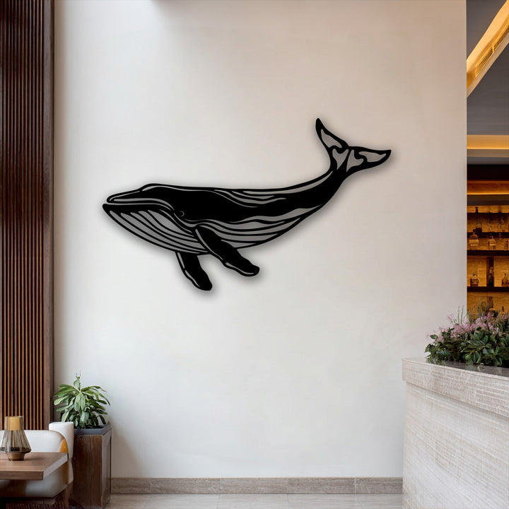 Lush purple and green plants adorn a marble counter in the foreground, complementing the elegant whale silhouette metal wall decor.