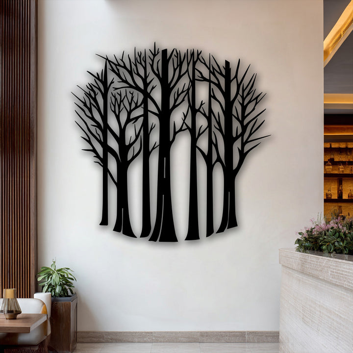 Striking color contrast in this metal artwork highlights bare forest tree silhouettes in deep black against a bright white wall.