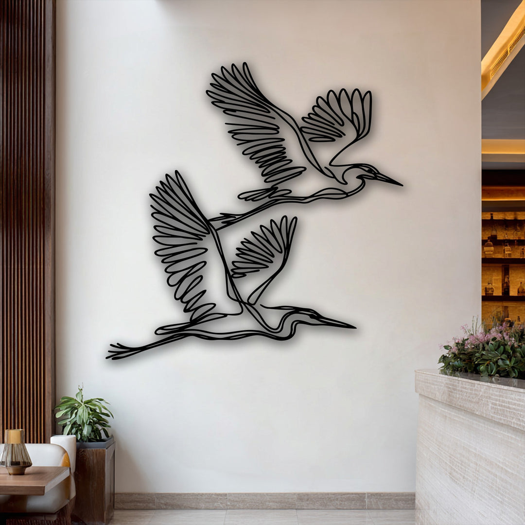 Delicate pink blossoms gently adorn the light counter, beautifully contrasting the graceful herons minimalist metal decoration wall art.