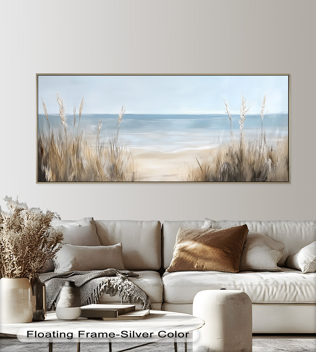 This serene coastal painting captures a soft, sandy beach bordered by tall grasses, leading the eye to calm, pale blue waters under a peaceful sky.

