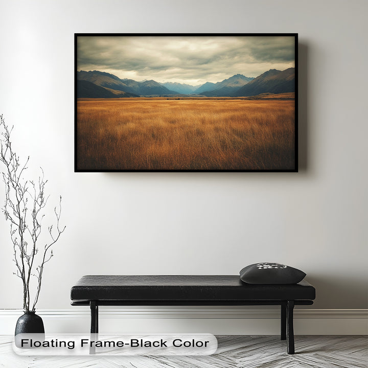 Serene mountain valley scene with golden grasslands and moody skies.
