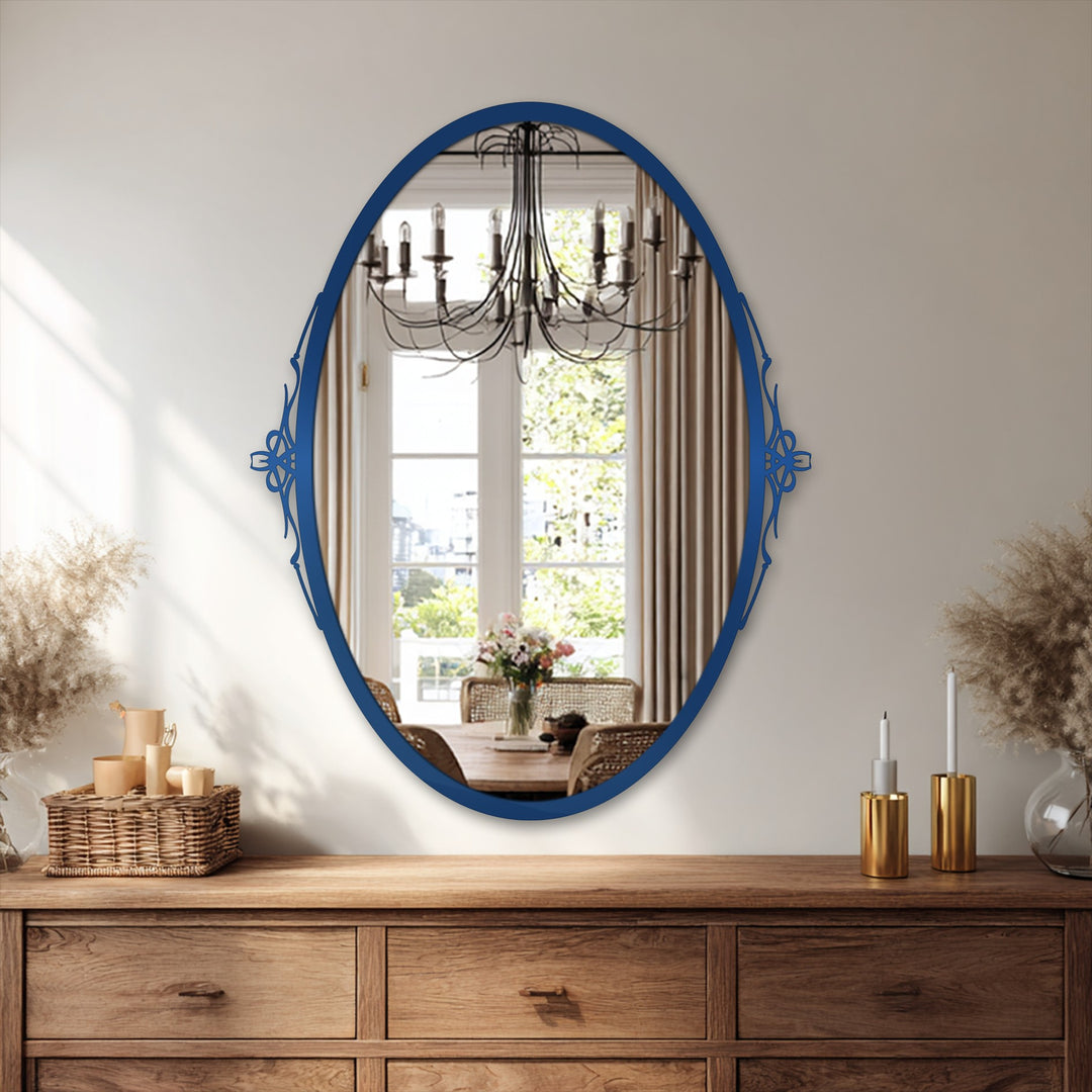 Deep blue contrasts against the light beige wall around this elegant simplicity oval framed wall mirror reflecting a chandelier and dining area.