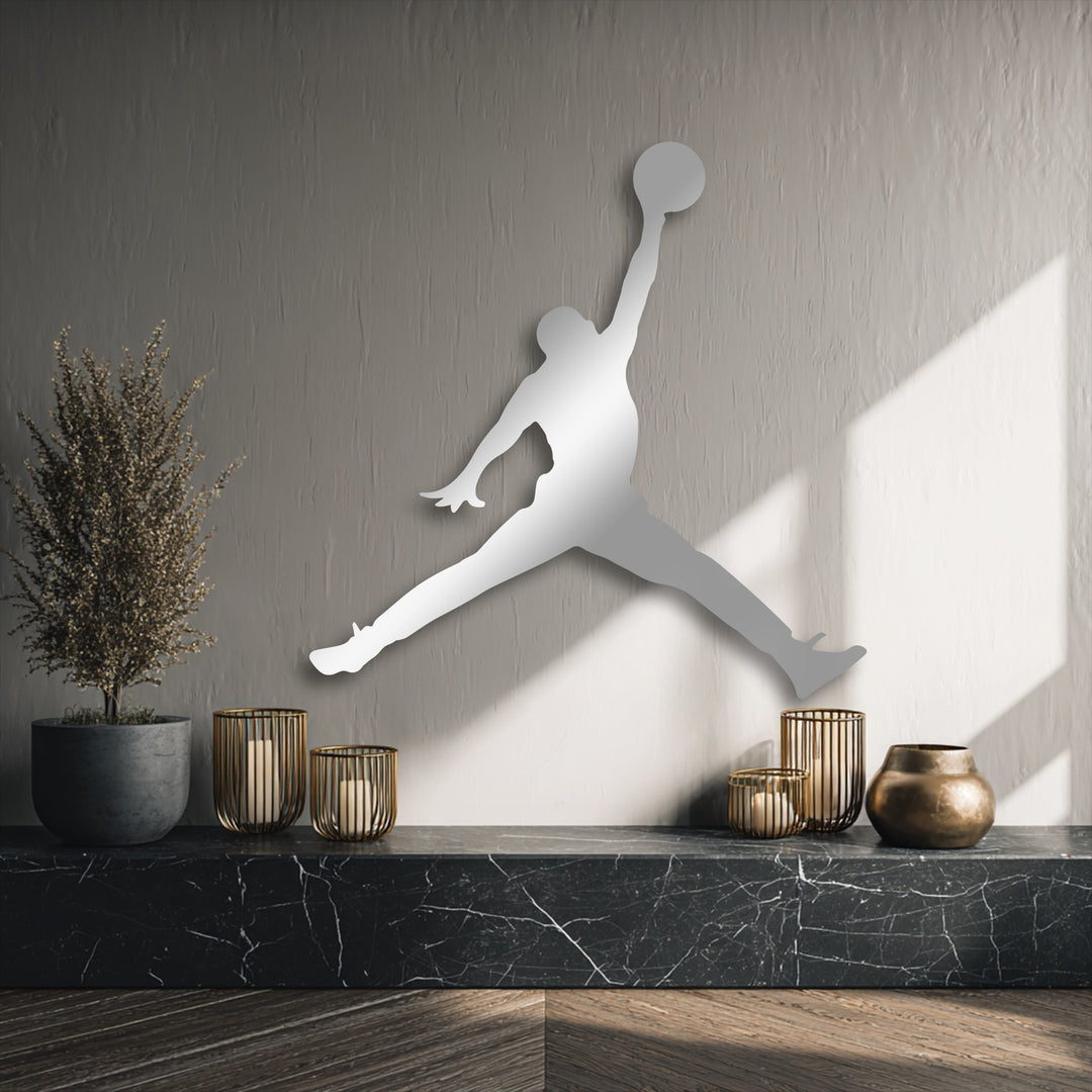 A dynamically oriented, elongated silhouette of a basketball jump player forms striking metal decoration wall art against a textured grey background.