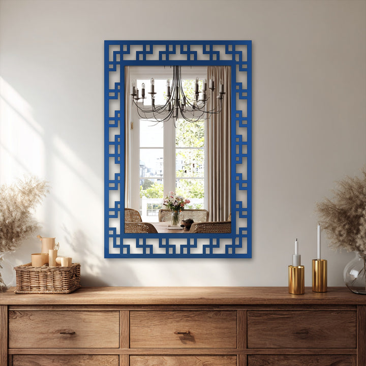 Reflected in this modern mirror, a dining room scene is layered with a chandelier, table setting, and garden view, adding depth behind the framed geometric design.