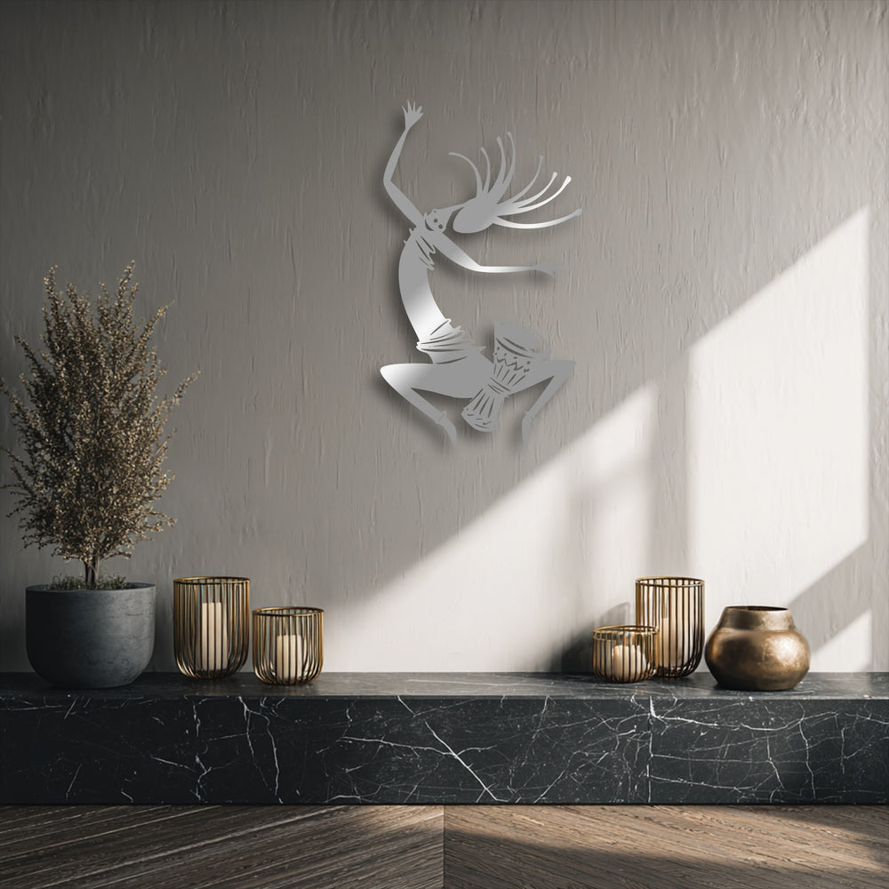 The layered effect of the energetic tribal dancer metal artwork creates dynamic depth as it floats above a textured wall, highlighted by natural light.