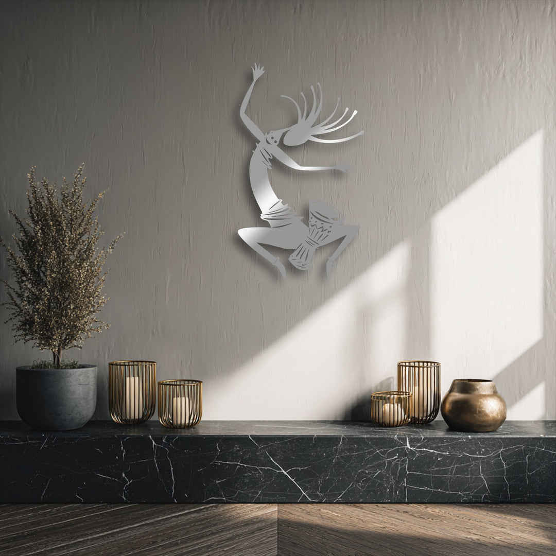 The layered effect of the energetic tribal dancer metal artwork creates dynamic depth as it floats above a textured wall, highlighted by natural light.