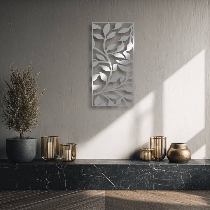 The focal point is a sleek abstract leaf branch pattern, a modern botanical metal artwork casting soft shadows on a textured wall.
