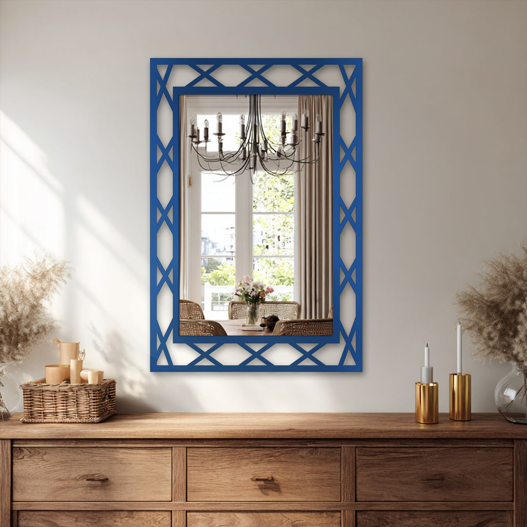 With striking color saturation, a framed wall mirror reflects a brightly lit dining room, contrasting the dark blue diamond lattice frame and its ornate details.