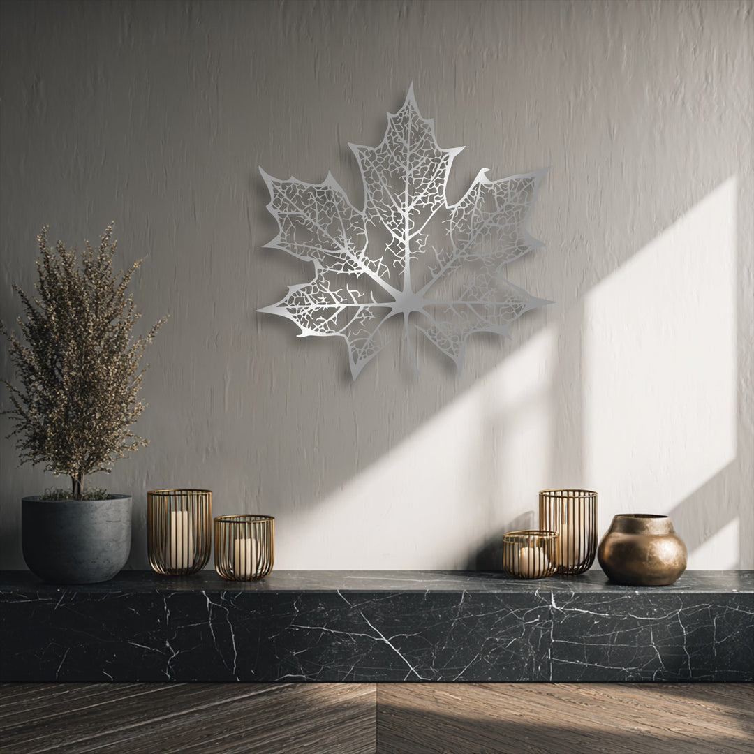 The striking focal point is an intricately cut, silver-toned maple leaf, a unique metal wall art piece with delicate vein patterns.