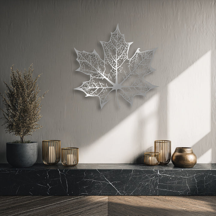 The striking focal point is an intricately cut, silver-toned maple leaf, a unique metal wall art piece with delicate vein patterns.