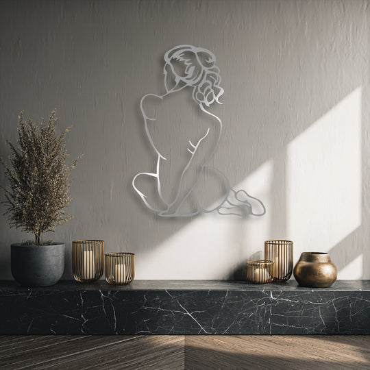 Dramatic light and shadow dance across the minimal female figure metal wall decor, highlighting its elegant silhouette against a textured wall.