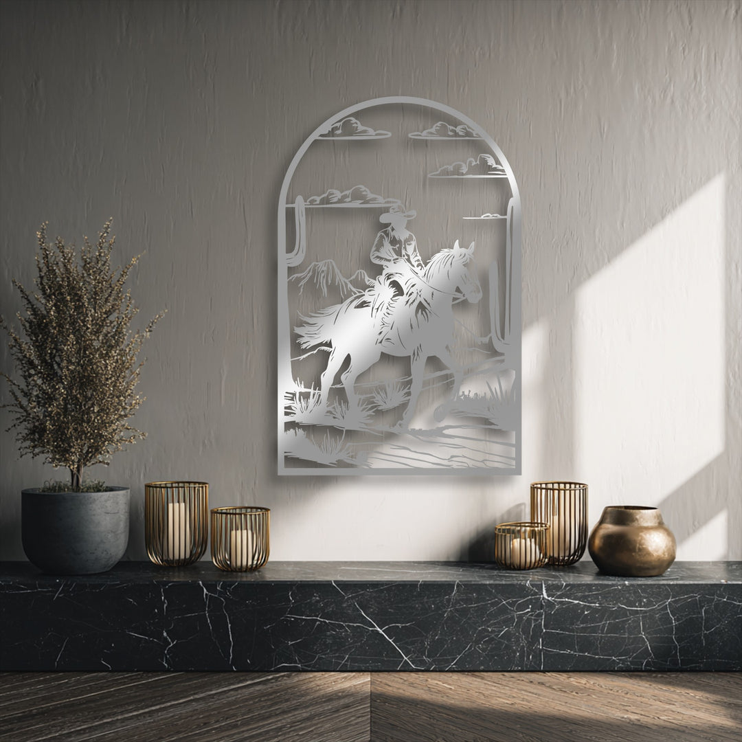 The intricate negative space defines the western metal artwork of a cowboy on horseback traversing a desert landscape.