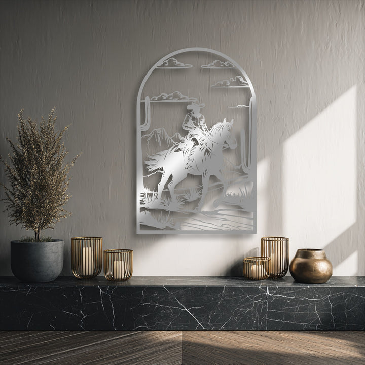 The intricate negative space defines the western metal artwork of a cowboy on horseback traversing a desert landscape.