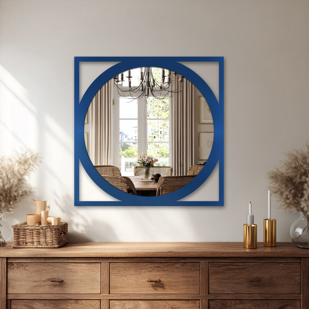 A rustic wooden dresser displays a decorative metal art basket filled with small containers and tall vases with pampas grass on either side of a striking framed wall mirror.