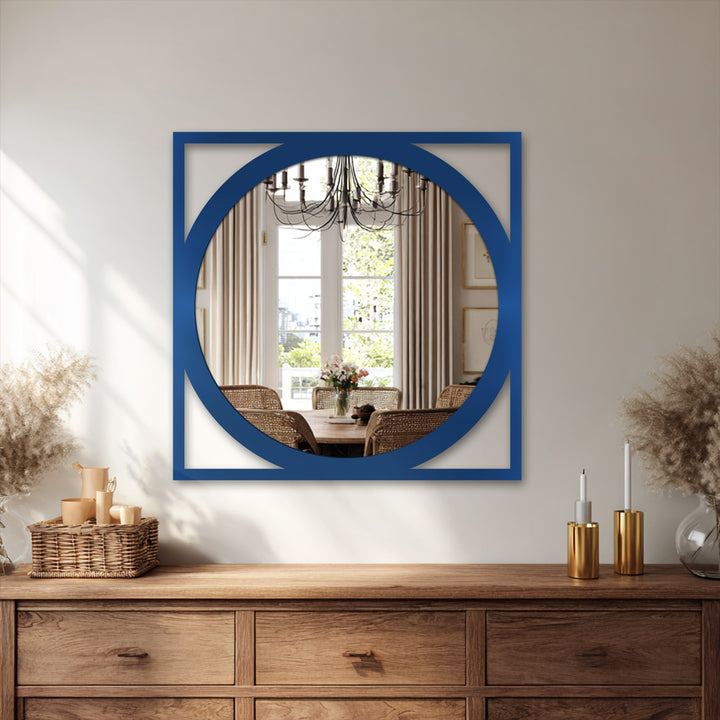 A rustic wooden dresser displays a decorative metal art basket filled with small containers and tall vases with pampas grass on either side of a striking framed wall mirror.