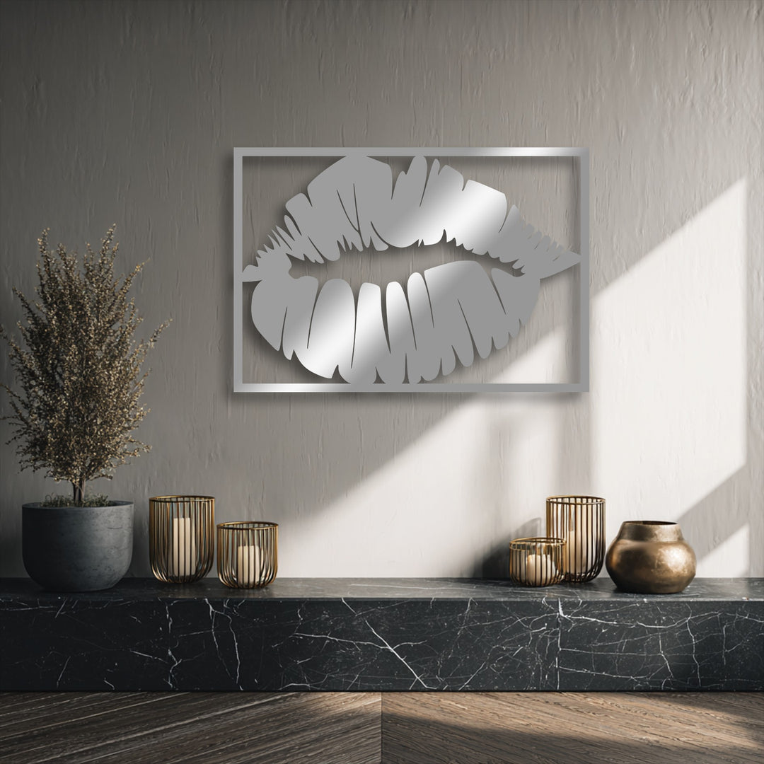The strong rectangular frame and stylized, angular contours of the lips form a striking piece of decorative metal art with reflective light patterns.