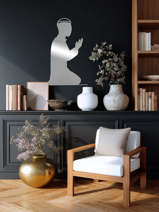 Gentle highlights illuminate the praying figure in this decorative metal art silhouette, casting a soft glow across the surrounding books and vases.