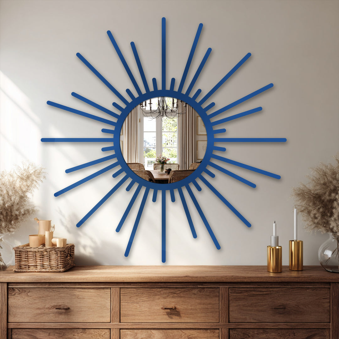 Reflected in the modern wall mirrors is a dining room setting with neutral-toned curtains, a chandelier, and furniture, setting the scene behind the sunburst mirror.