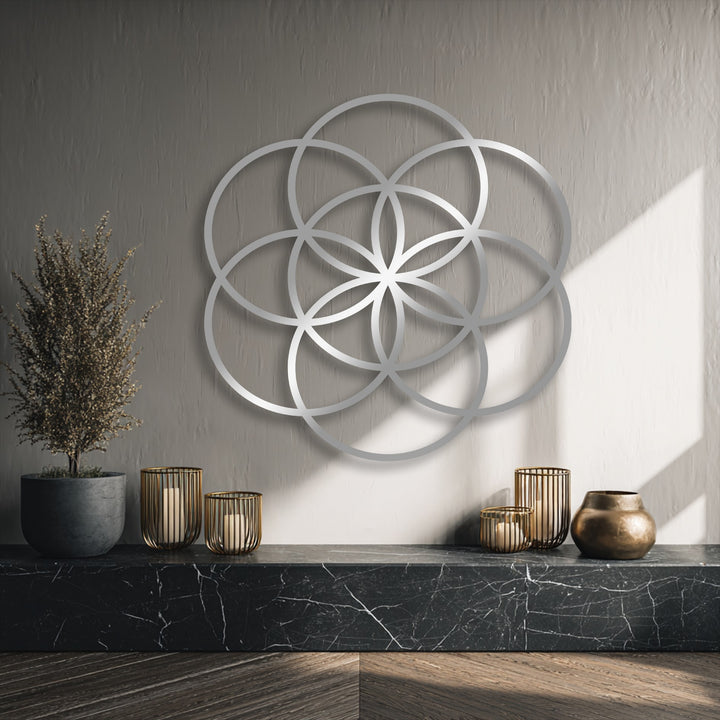 The centerpiece is a gleaming silver Flower of Life geometric metal wall decor, casting soft shadows on the textured wall.