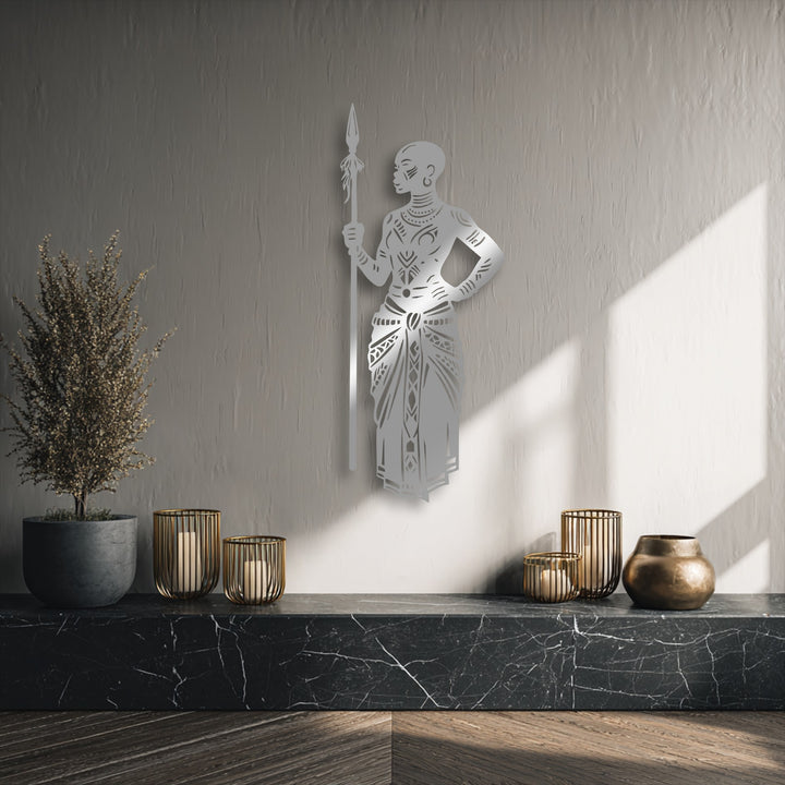 Highlighting depth, the silver tribal African warrior metal wall decor offers a layered silhouette against the textured wall, with shadows adding rich dimension.
