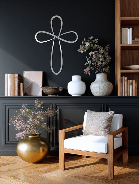 Silvery metal art for wall forms a high color contrast with the dark paneled wall behind it, showcasing the Infinite Grace loop cross.