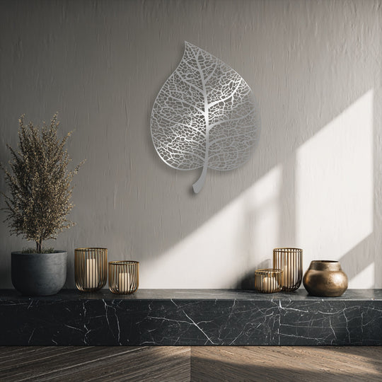 The elegant metal art for wall depicts an intricate botanical leaf silhouette, its delicate veins seemingly swaying with the shifting light and shadows.