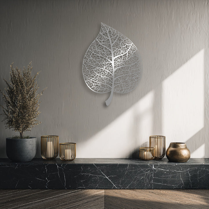 The elegant metal art for wall depicts an intricate botanical leaf silhouette, its delicate veins seemingly swaying with the shifting light and shadows.