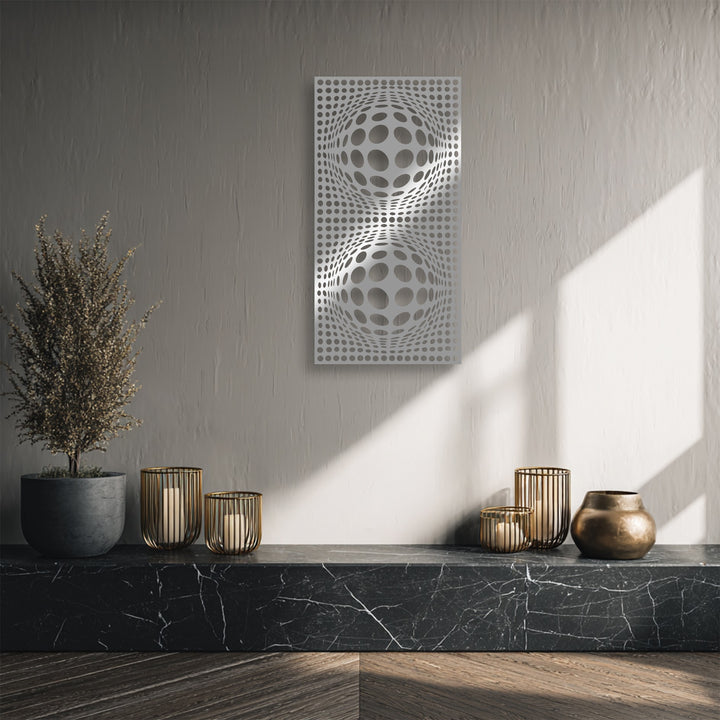 Subdued color saturation highlights the striking hypnotic orb geometry metal wall decor, flanked by a dried plant and bronze vessels.