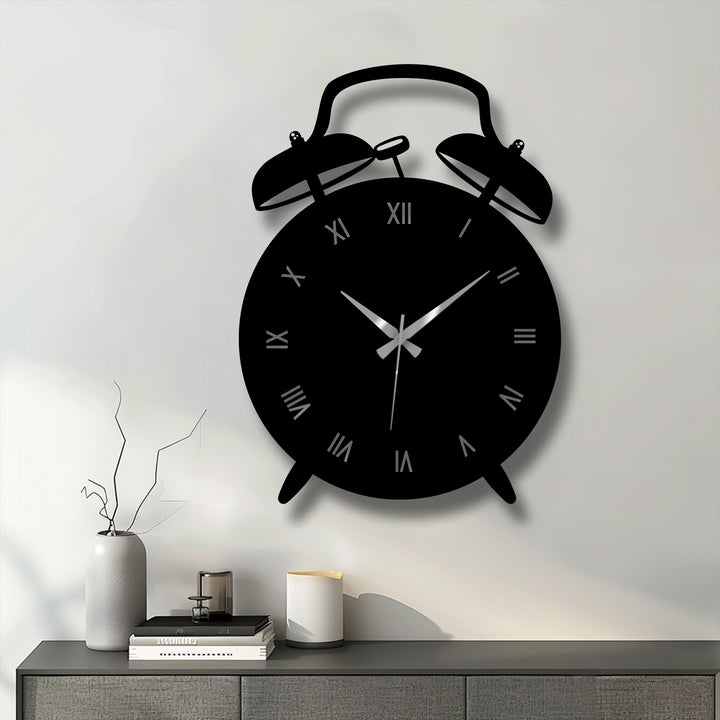 Foreground view of a vintage alarm clock-shaped decorative metal art clock featuring Roman numerals on a gray cabinet in a modern room.