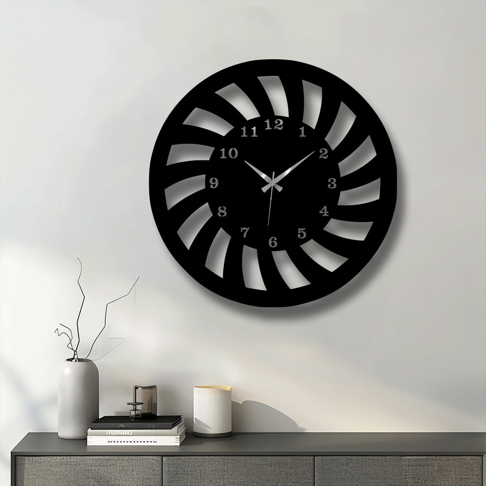 The prominent black spiral motion metal wall clock, a piece of unique metal wall art, features a dynamic design on a white wall.