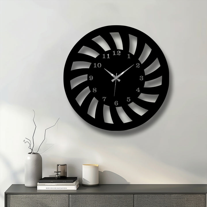 The prominent black spiral motion metal wall clock, a piece of unique metal wall art, features a dynamic design on a white wall.