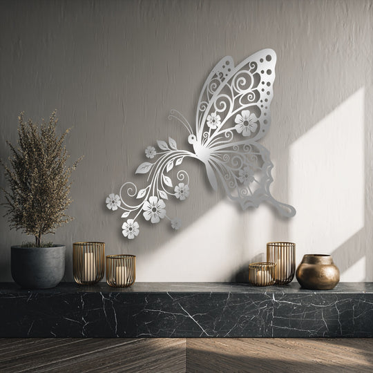 A dark marbled countertop holds three glowing gold candle holders and a bronze vase beneath elegant butterfly floral metal art for wall.