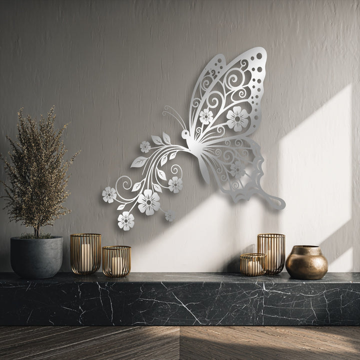 A dark marbled countertop holds three glowing gold candle holders and a bronze vase beneath elegant butterfly floral metal art for wall.