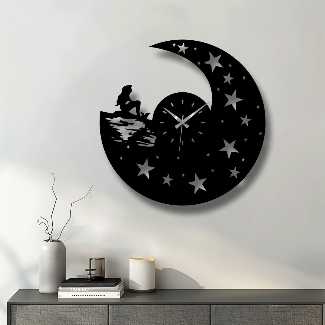 Horizontally oriented circular metal artwork wall clock features a celestial night design with a crescent moon, stars, and a mermaid silhouette.
